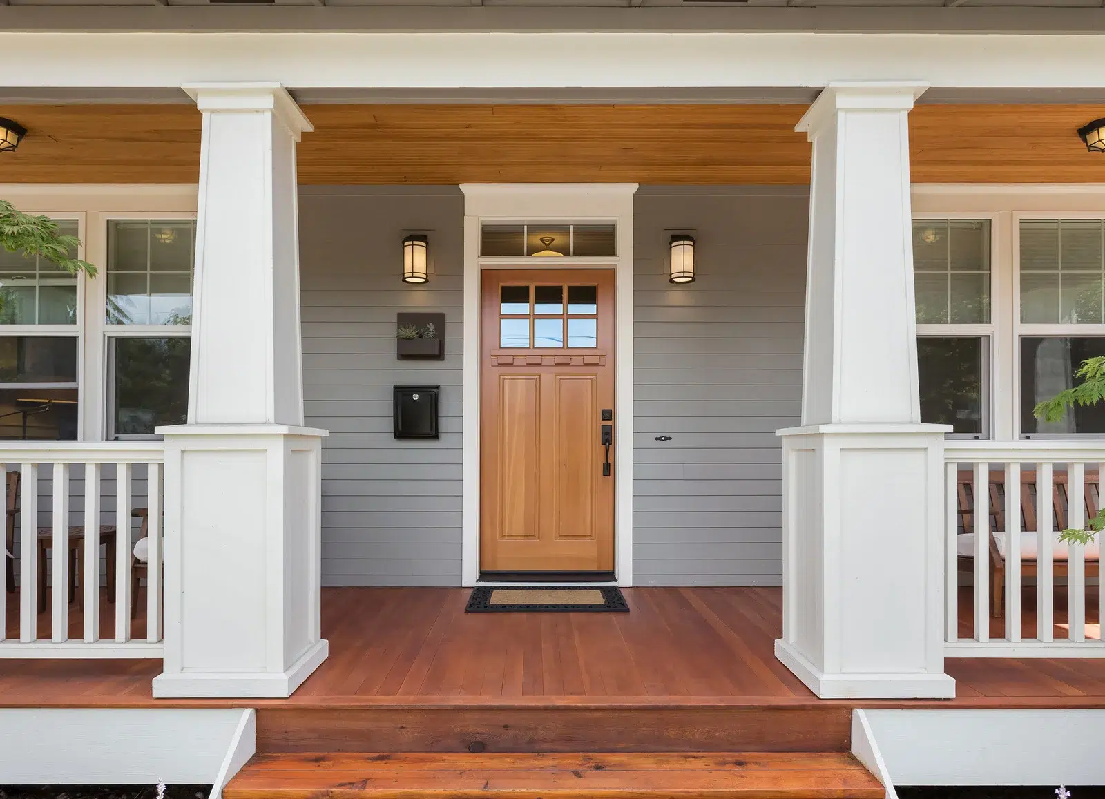 The front door of a residential home, the door and deck flooring are made of finished wood.