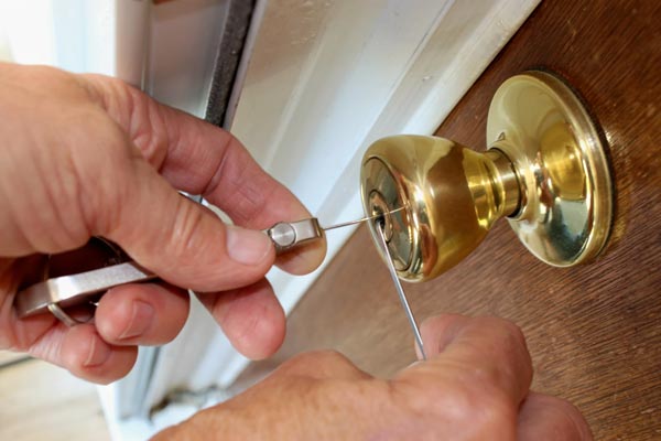 Lock pick tools are used to unlock a residential door knob lock.